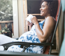 Image of a pregnant woman sitting on a chair and holding a mug.