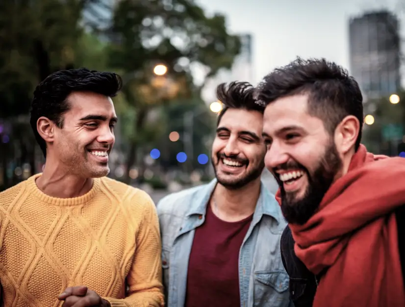 A group of three young men laughing together in the city