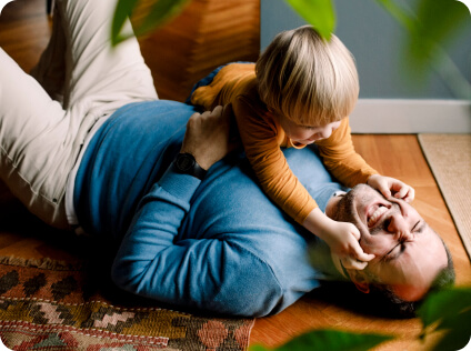 Playful daughter pinching father's cheeks on the floor at home